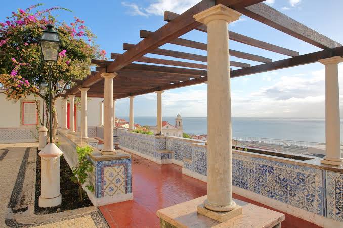 Terrace with pergola, tiled columns, and ocean view.