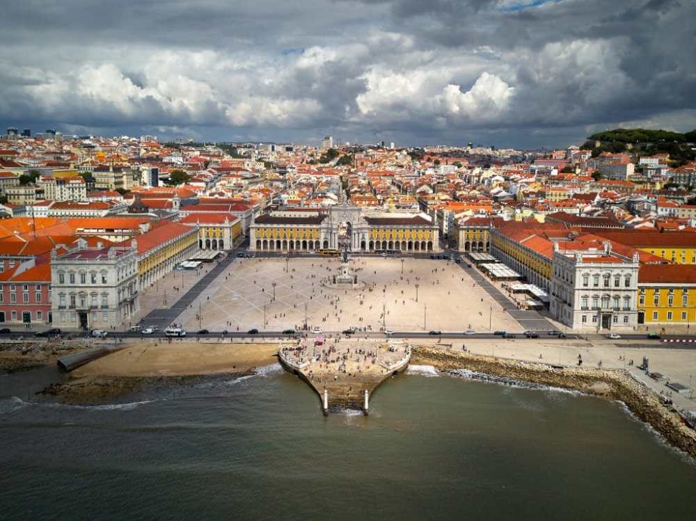 Aerial view of a large, historic square with colorful buildings and waterfront.