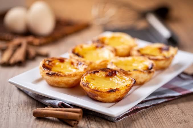 Tray of Portuguese custard tarts on a wooden table.